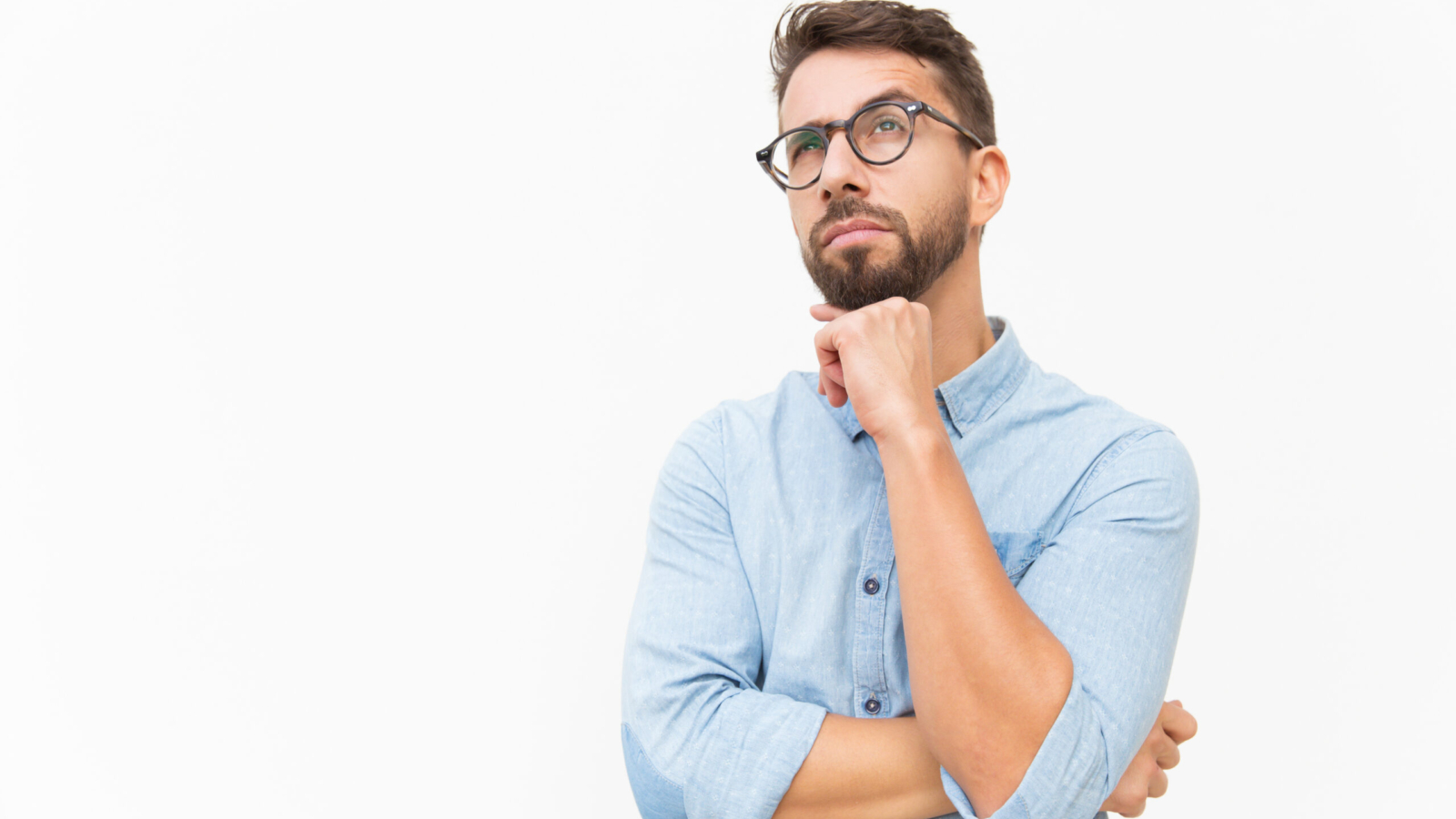 Pensive customer thinking over special offer, touching chin, looking up. Handsome young man in casual shirt and glasses standing isolated over white background. Advertising concept
